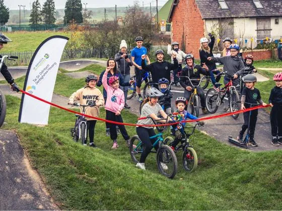 A group of children and adults celebrate behind a red rope for the Actif Denbighshire Project.
