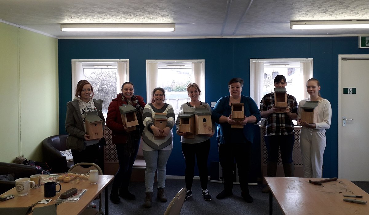 A small group of women standing in Pengwern Community Centre in Llangollen showing their bird box building
