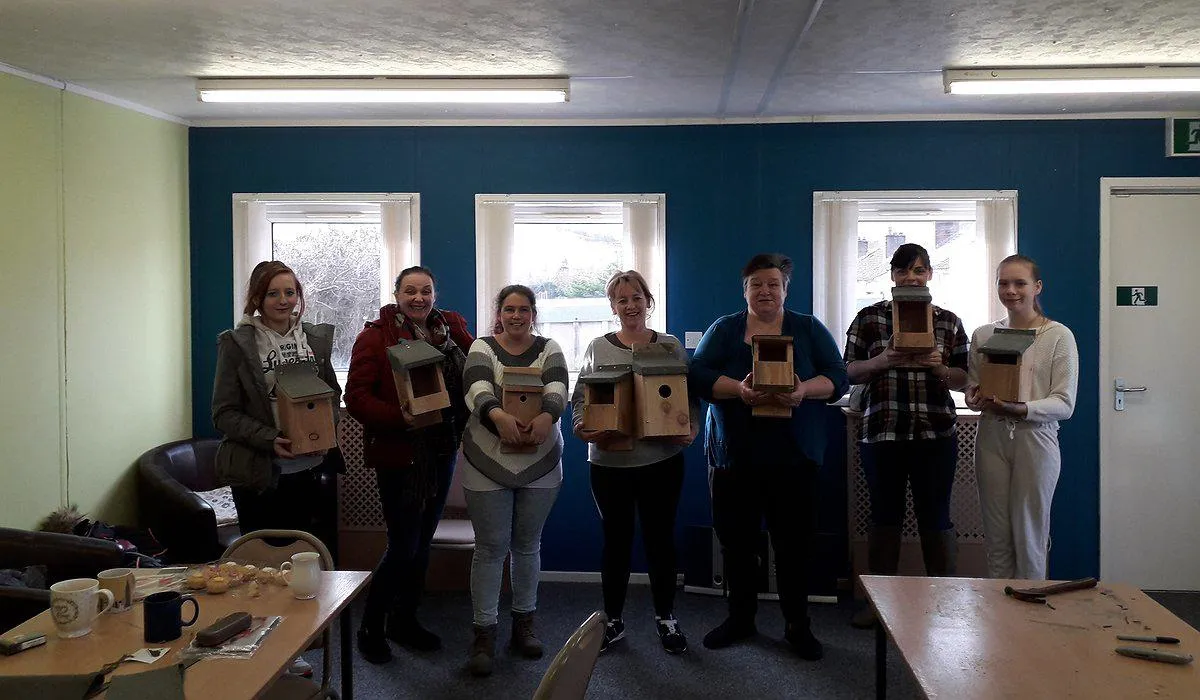 A small group of women standing in Pengwern Community Centre in Llangollen showing their bird box building