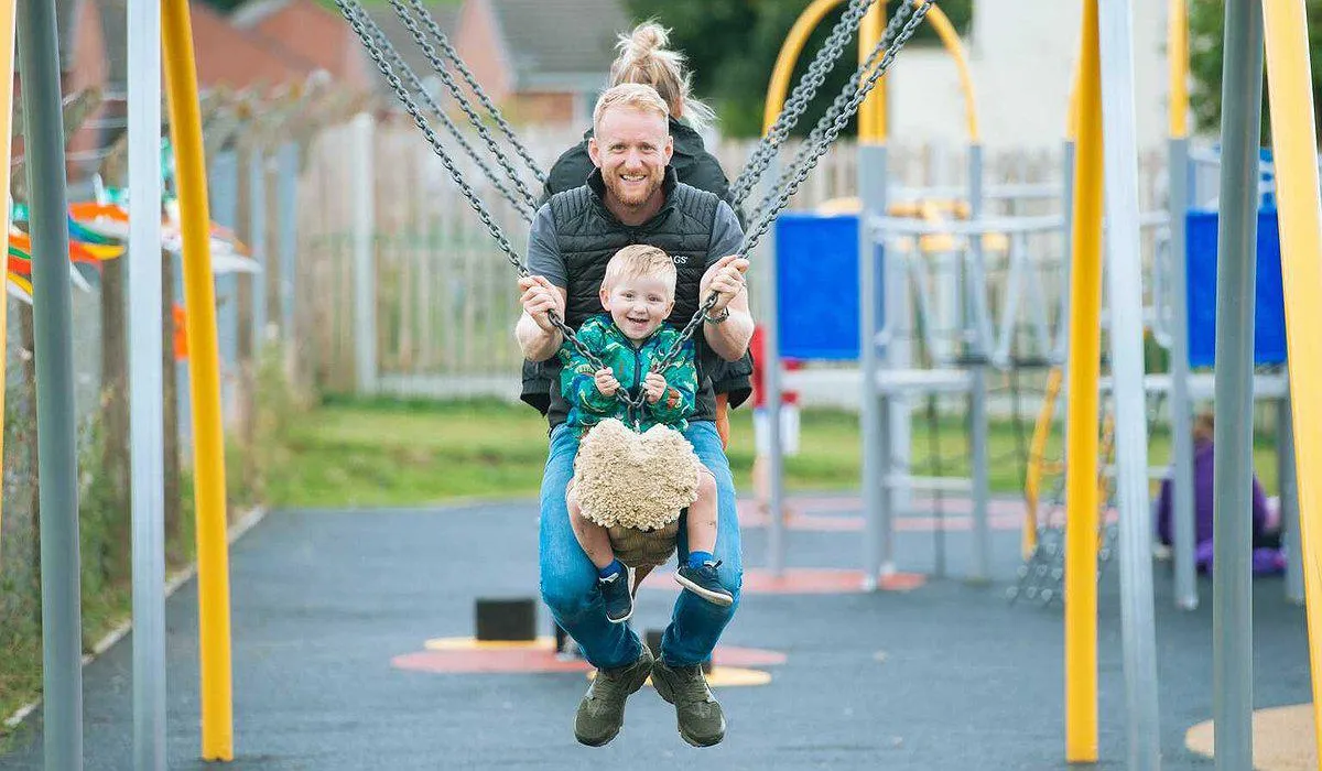 A family of 3 playing on a new rope swing in Ruthin