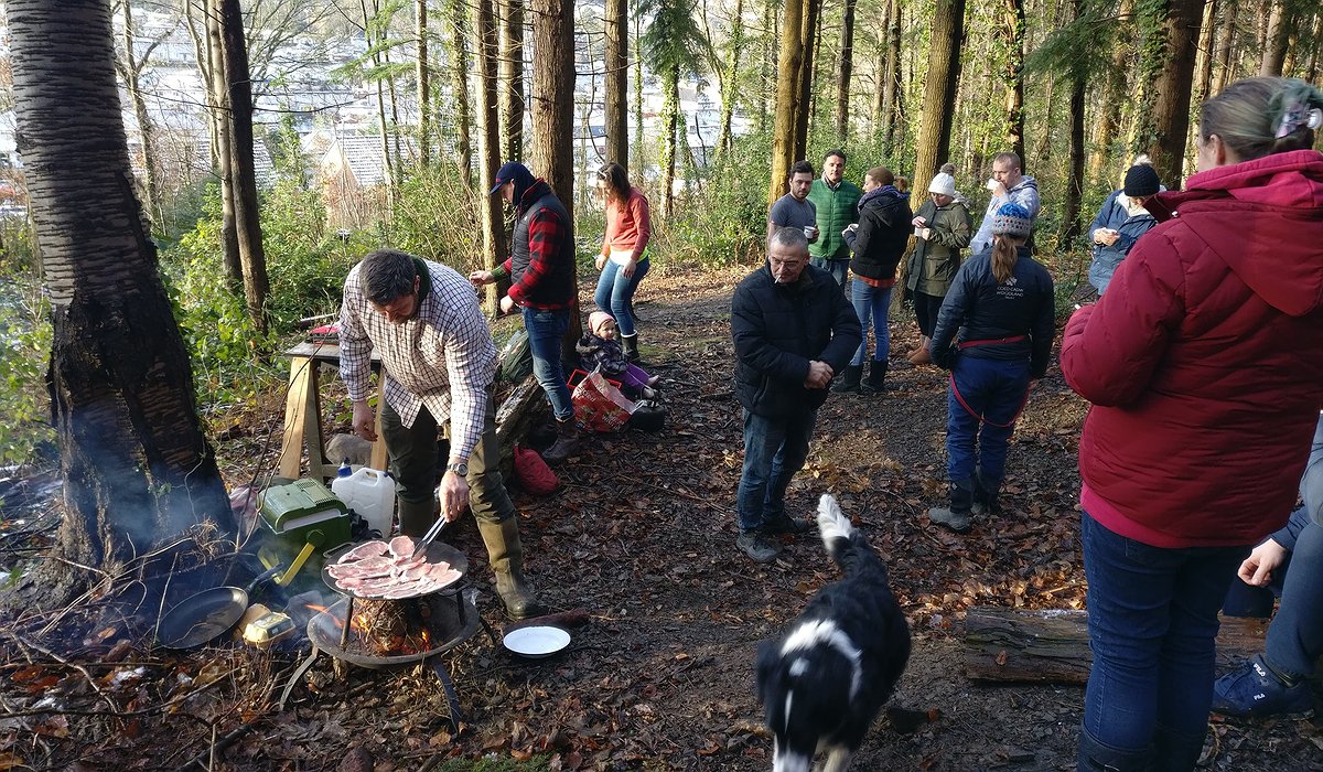A group of children and adults having breakfast in the woods at Pengwern, Llangollen