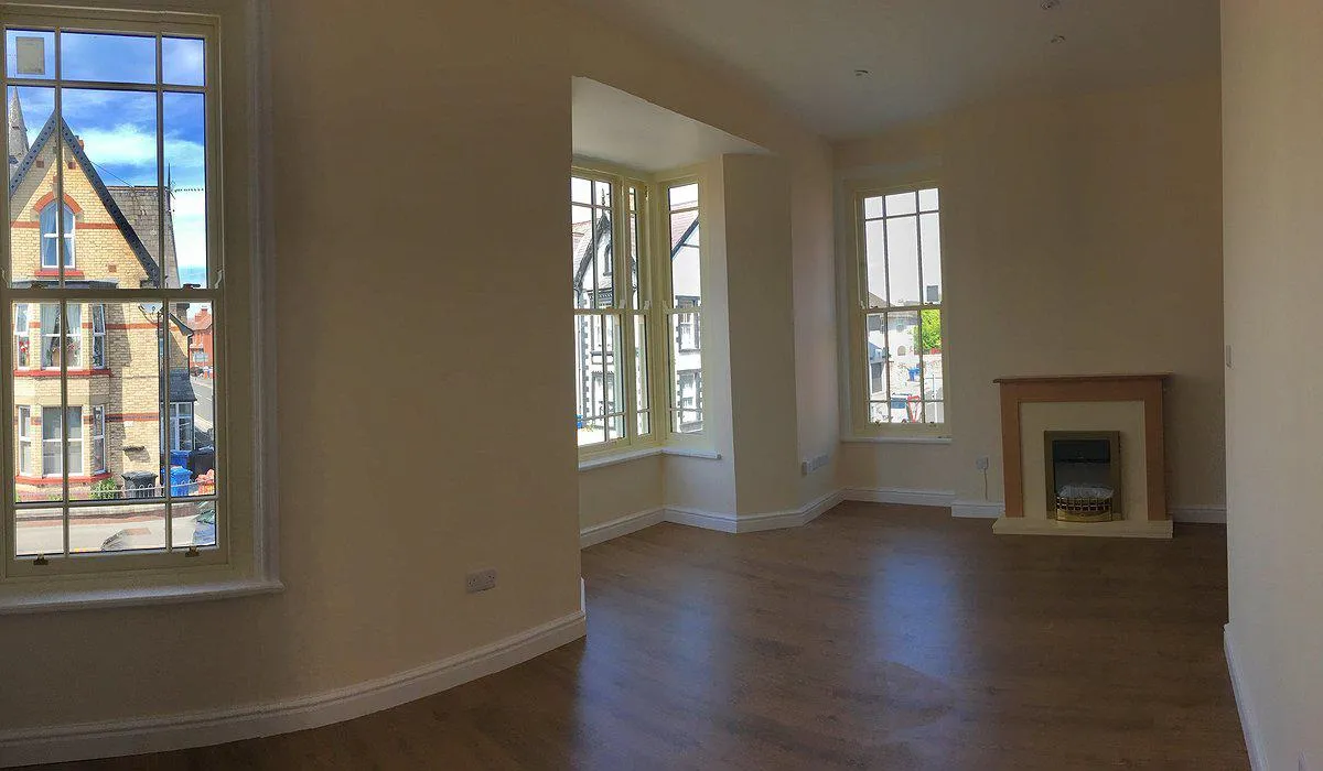 Cream coloured room with fireplace and 3 windows