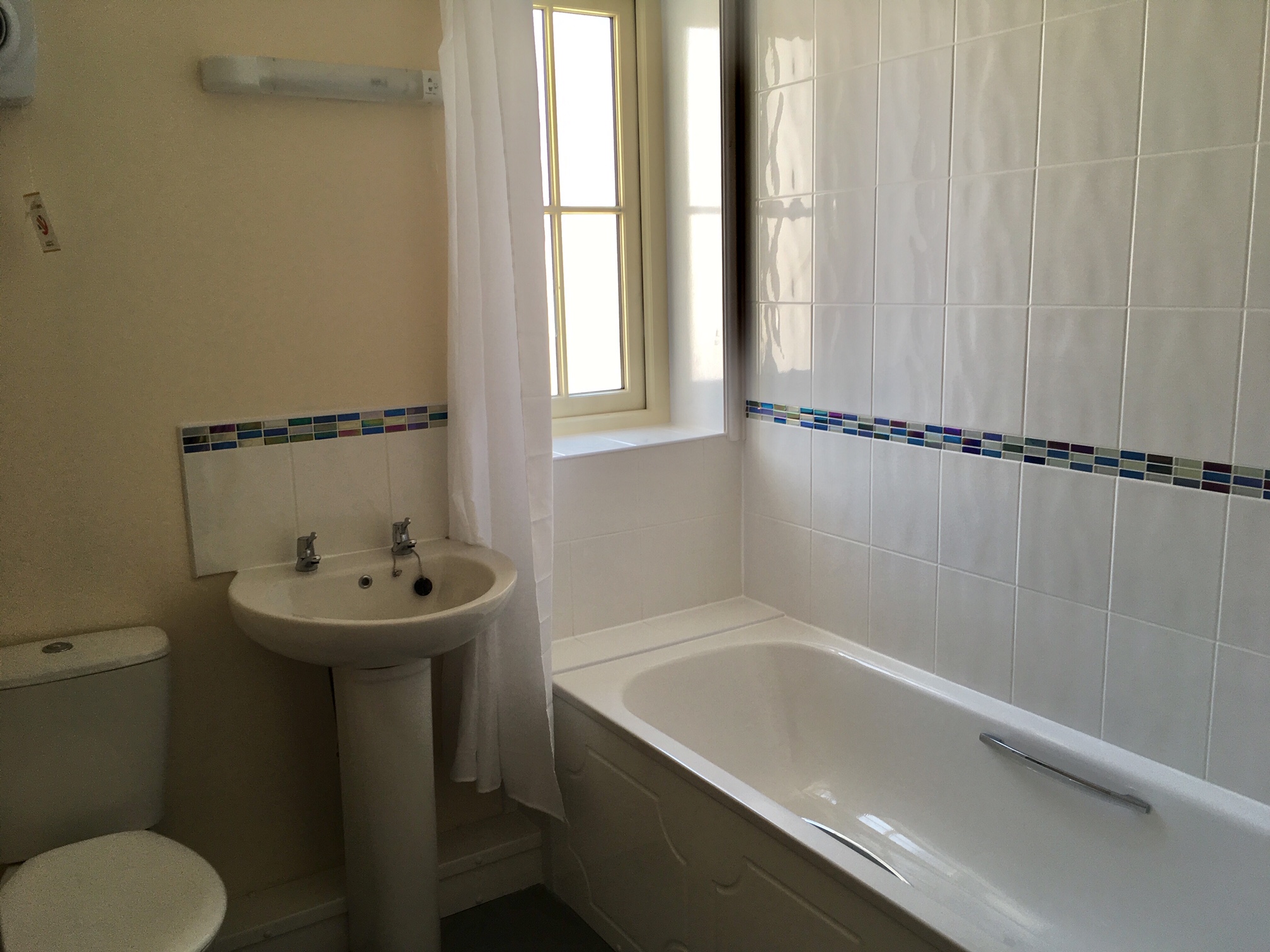 A new white bathroom suite with over the bath shower