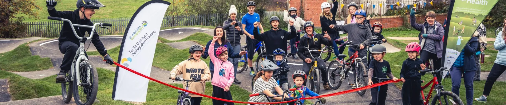 Group of young children and adults on a bike pump track.