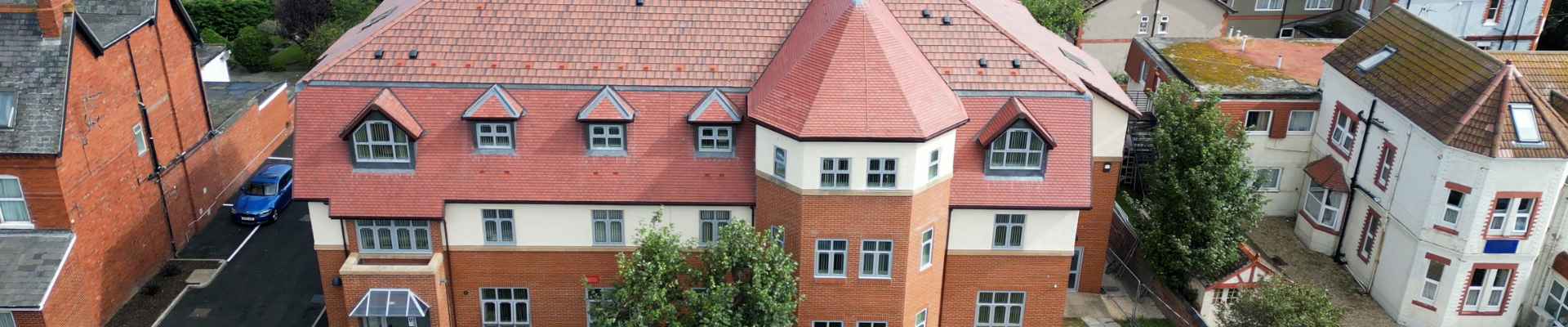 Three-storey red bricked building with a pitched red tile roof. 