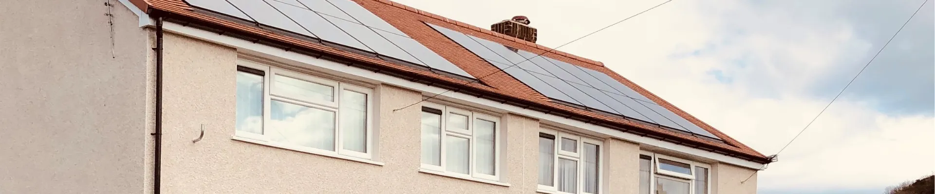 Cream rendered two storey property with a red tiled roof and solar panels.