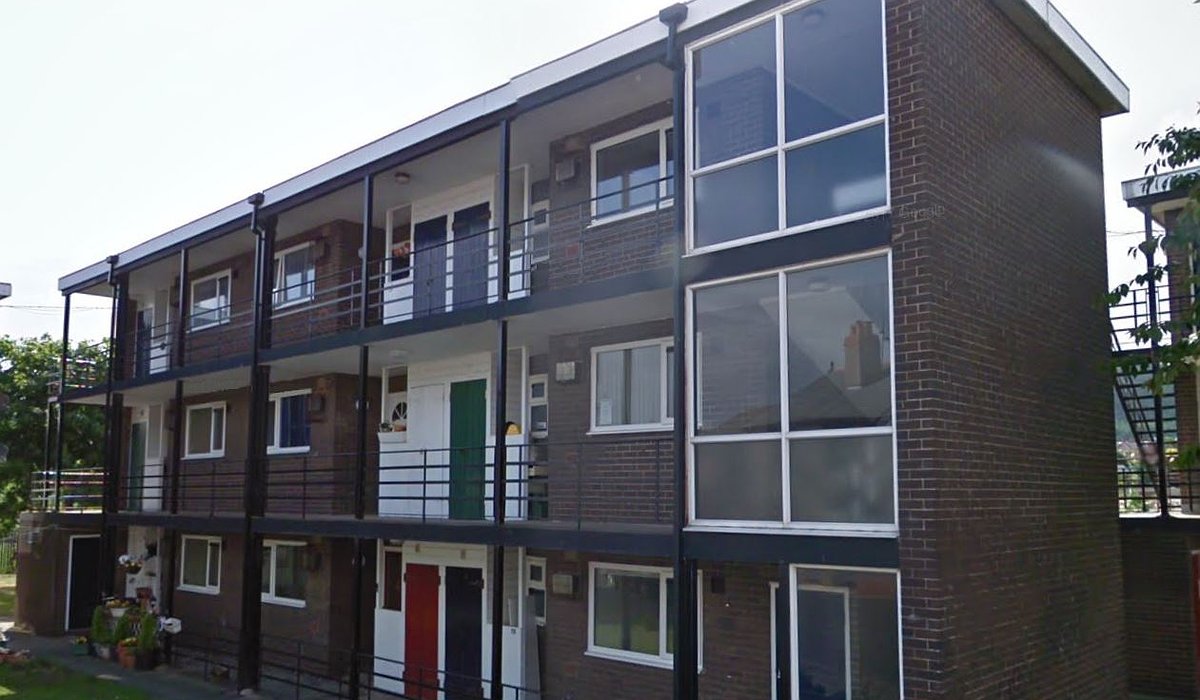 Old style flats in Caradoc Road, Prestatyn. The flats have a brown exterior with railed balconies.