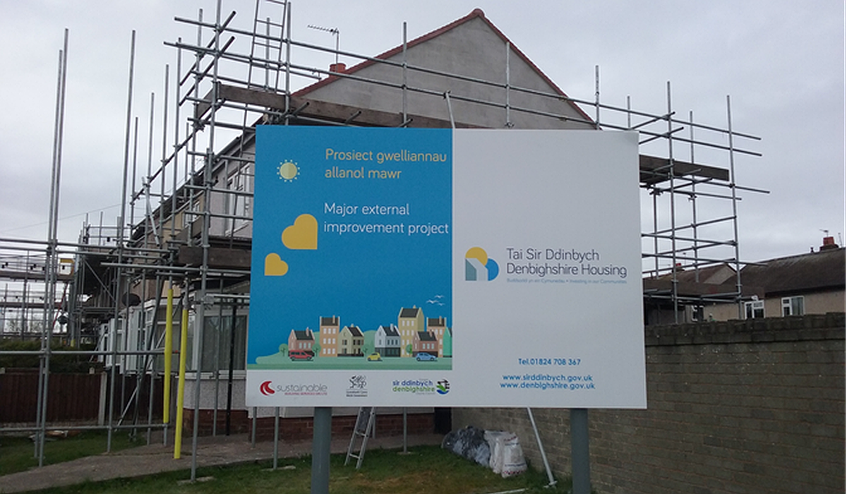 A sign by a house that says Improvement programme of properties by Denbighshire Housing
