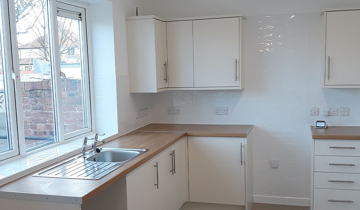 New kitchen in an empty property with white units and doors.