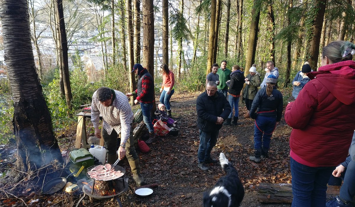 A group of children and adults having breakfast in the woods – Pengwern, Llangollen.