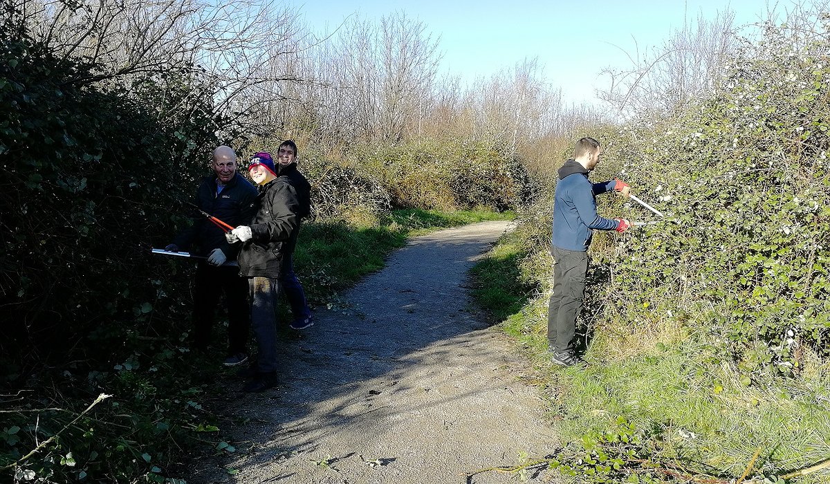 Three men taking part in conservation work, trimming hedges in Rhyl as part of the Nature for Health project.