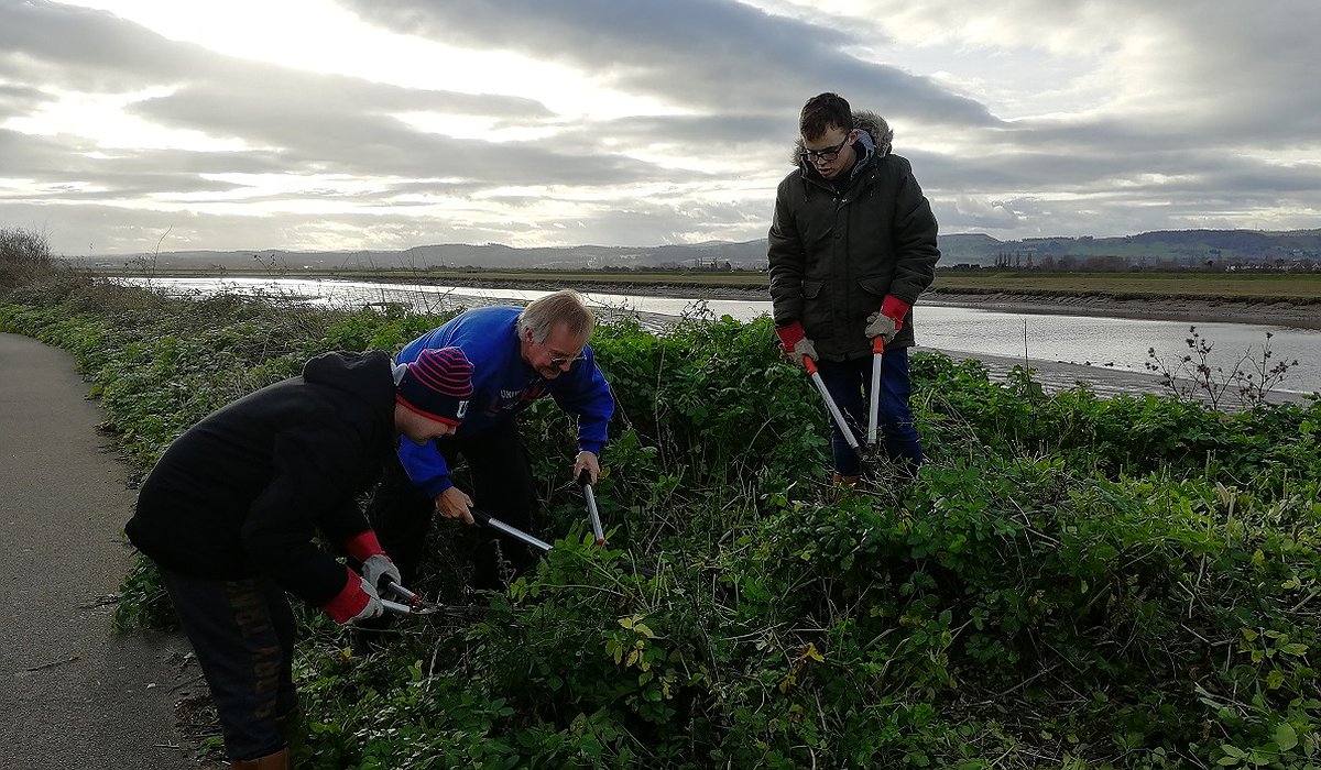 Men taking part in conservation work, clearing away verges at Rhyl as part of the Nature for Health project.