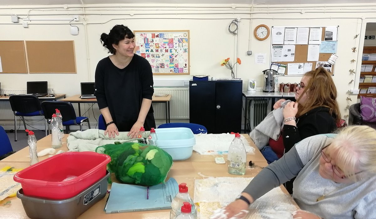 Older people taking part in a Nature for Health felt making workshop in Rhyl. Sat at a table inside a community centre.