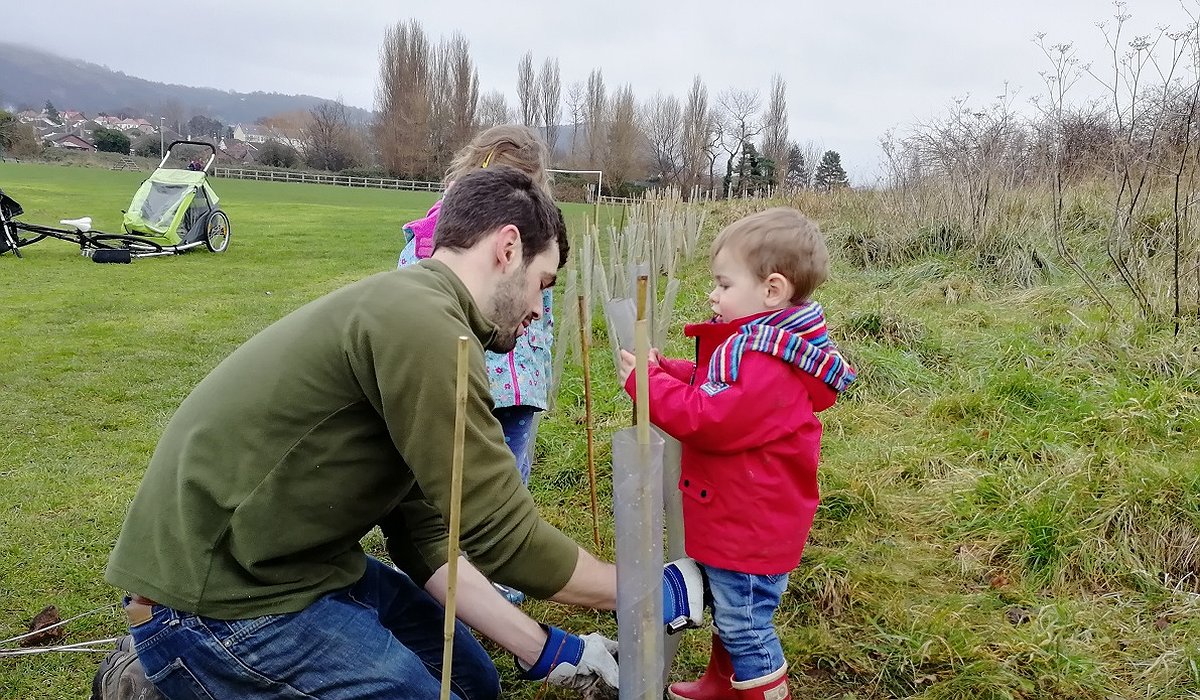 A young family helping plant a new hedge at the Morfa Gateway project, part of the Nature for Health project