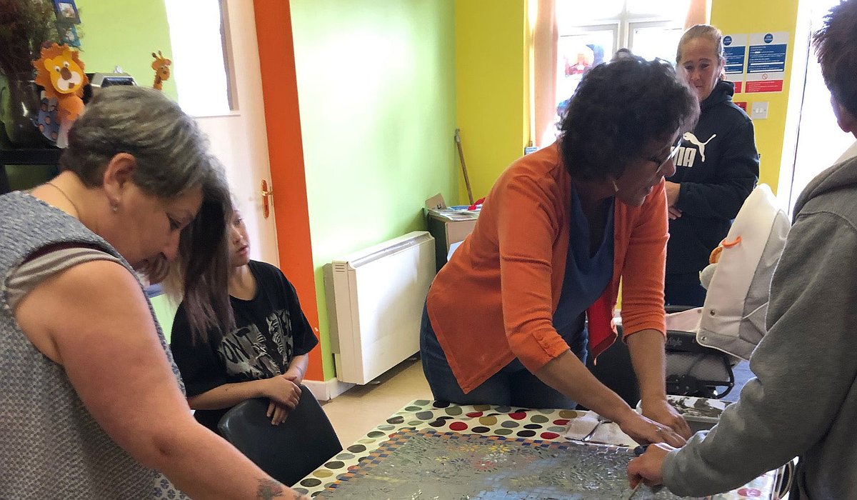 A group of women working at a table creating a colourful nature themed mosaic as part of the Nature for Health project.