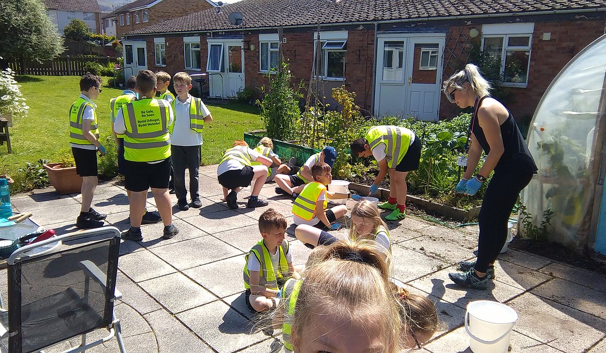 A group of young school children learning to keep gardens tidy at Llygadog Community Centre.