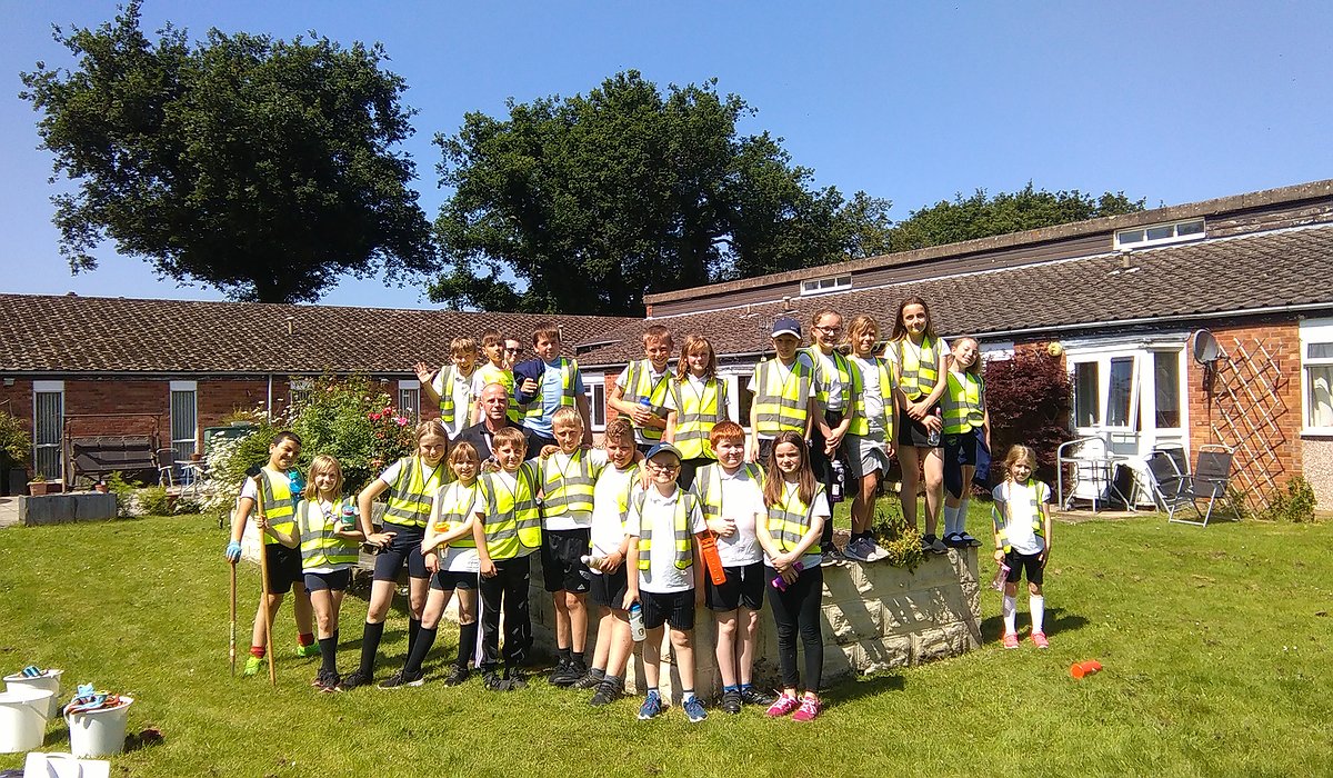 A large group of young school children learning to keep gardens tidy at Llygadog Community Centre.