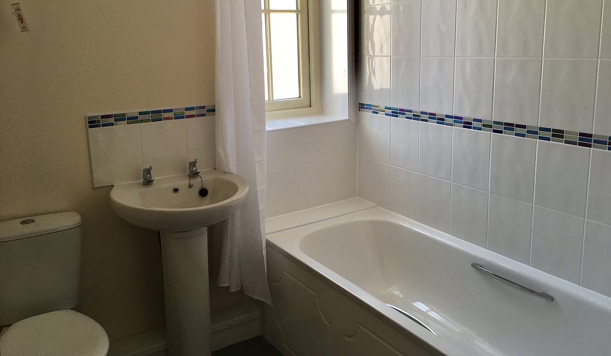 A new white bathroom suite with over the bath shower.